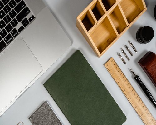 A flat-lay view of a workspace layout showing a writing device and an organic tea container