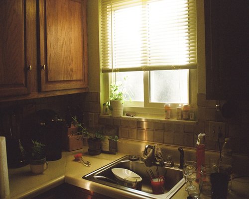A clean domestic kitchen interior with morning sunlight coming through the window panes